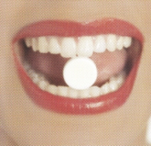 woman with birth control pill between her teeth