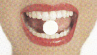 woman with birth control pill between her teeth