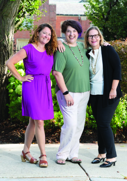Stephanie Jones Wagle ’97, Meredith Elkins ’91 and Perrin McCormick Menashi ’90 stand together outside with their arms on each other's shoulders.